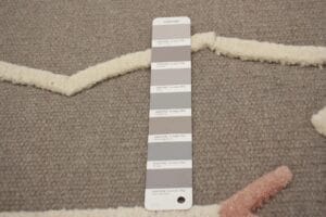 Pantone-kleurenstaal met verschillende grijstinten op een gestructureerd oppervlak.