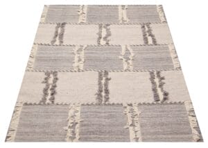 Dit rechthoekige tapijt heeft een boeiend patroon van afwisselend grijze en beige vierkanten, compleet met franjedetails.