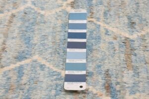 Een Pantone-kleurenstaal met verschillende tinten blauw op een blauw-wit vloerkleed.