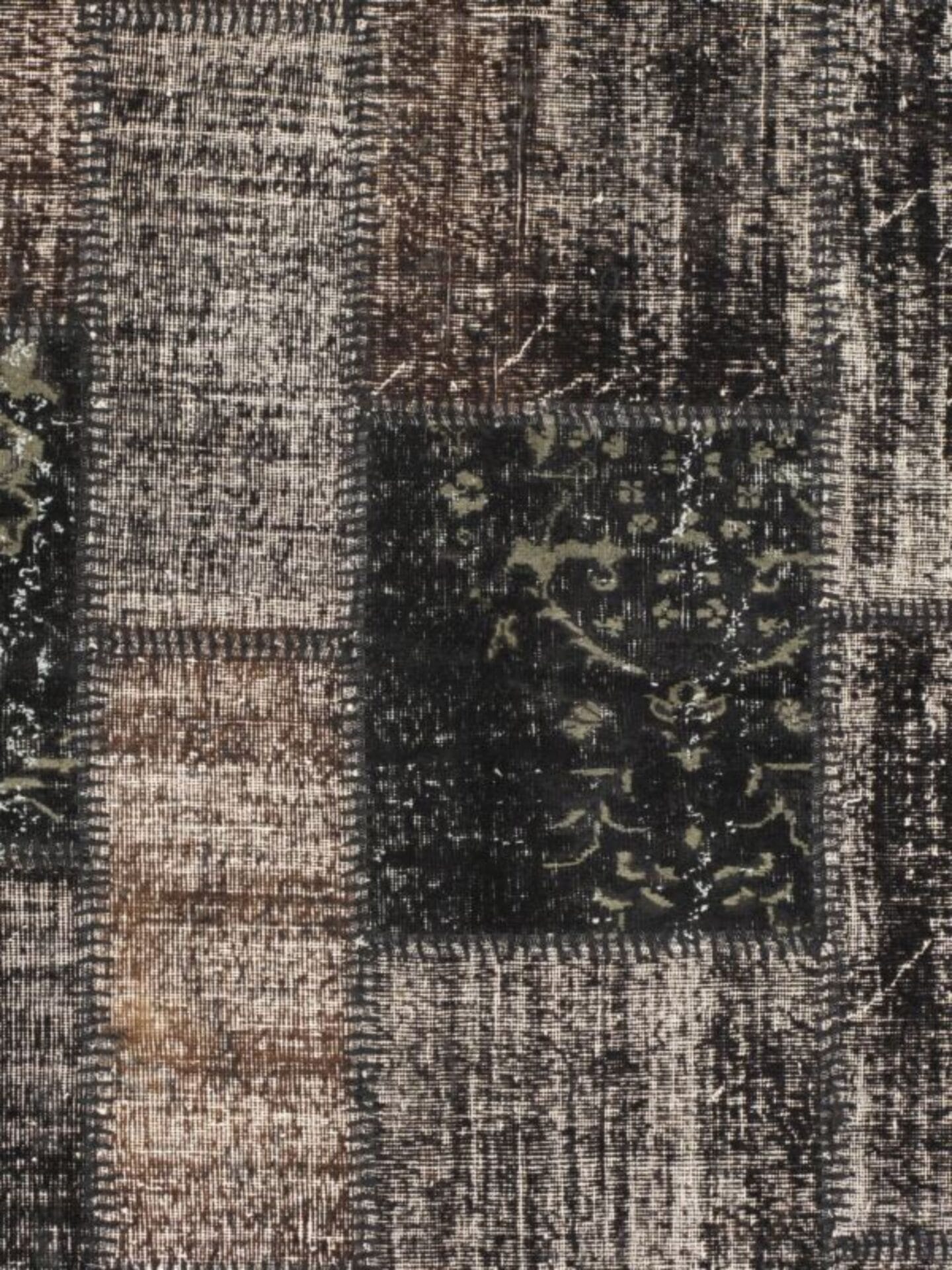 Een close-up van een rechthoekig vloerkleedpatroon met textuur, met tinten bruin, beige en zwart met een mix van verweerde en ingewikkelde ontwerpen.