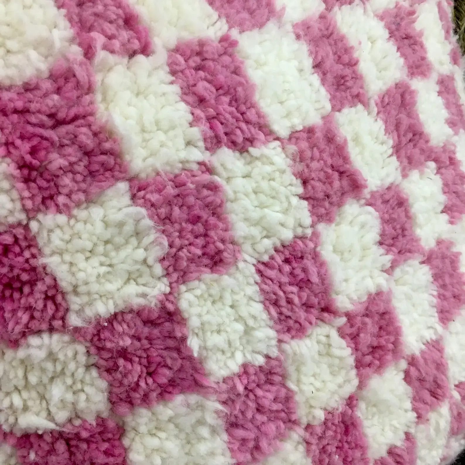 Close-up van een roze en wit geblokte, pluizige stoftextuur.