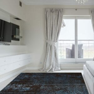 Een slaapkamer met een blauw en zwart tapijt.