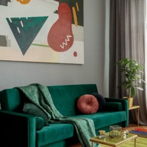 Een woonkamer met een groene bank, een kleurrijk schilderij en een vloerkleed.