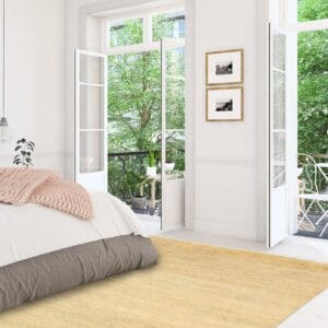 Een slaapkamer met een wit bed en een geel tapijt.