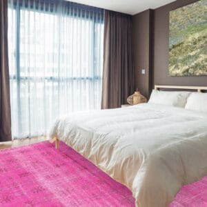 Een slaapkamer met een roze tapijt op de vloer.