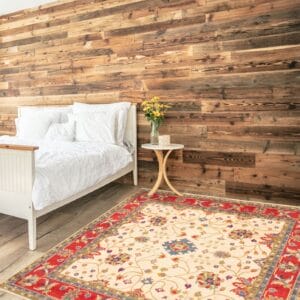 Een slaapkamer met een rood en beige tapijt voor een houten muur.