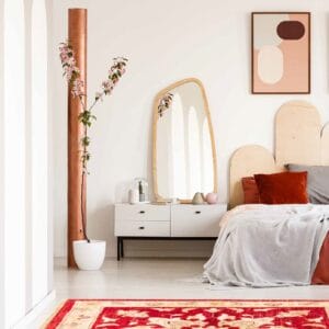 Een slaapkamer met een rood tapijt en een wit bed.