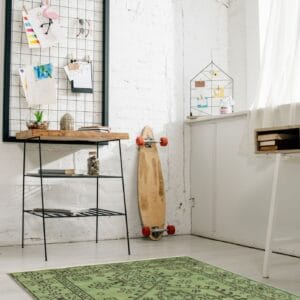 Een kamer met een groen vloerkleed en een skateboard.