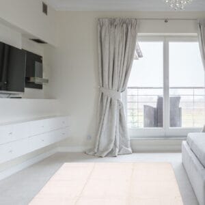 Een witte slaapkamer met een tv en een vloerkleed.