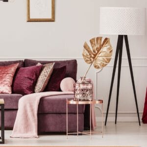 Een woonkamer met een paars vloerkleed en roze kussens.