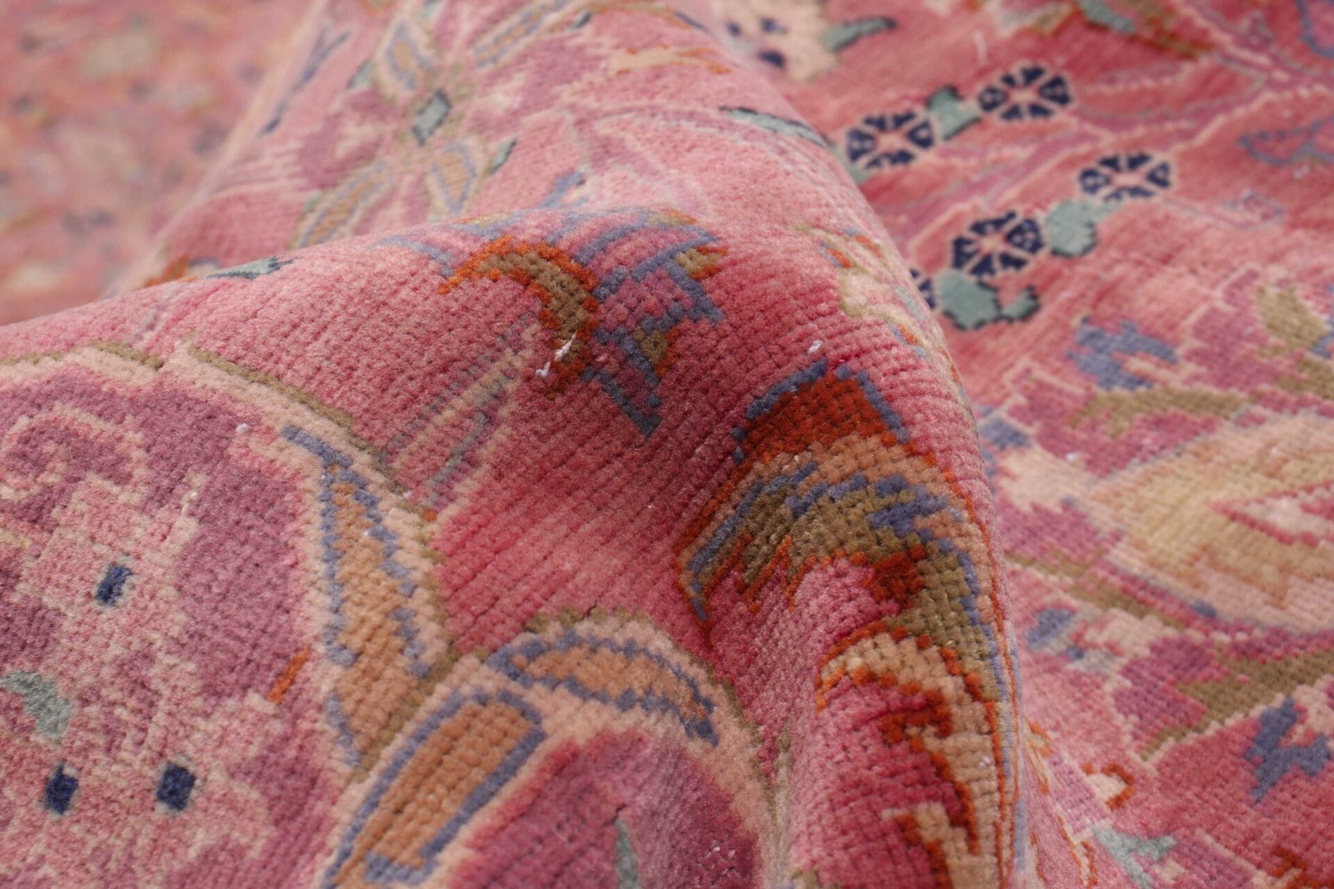 Beschrijving: Een close-up van een roze en blauw vloerkleed.