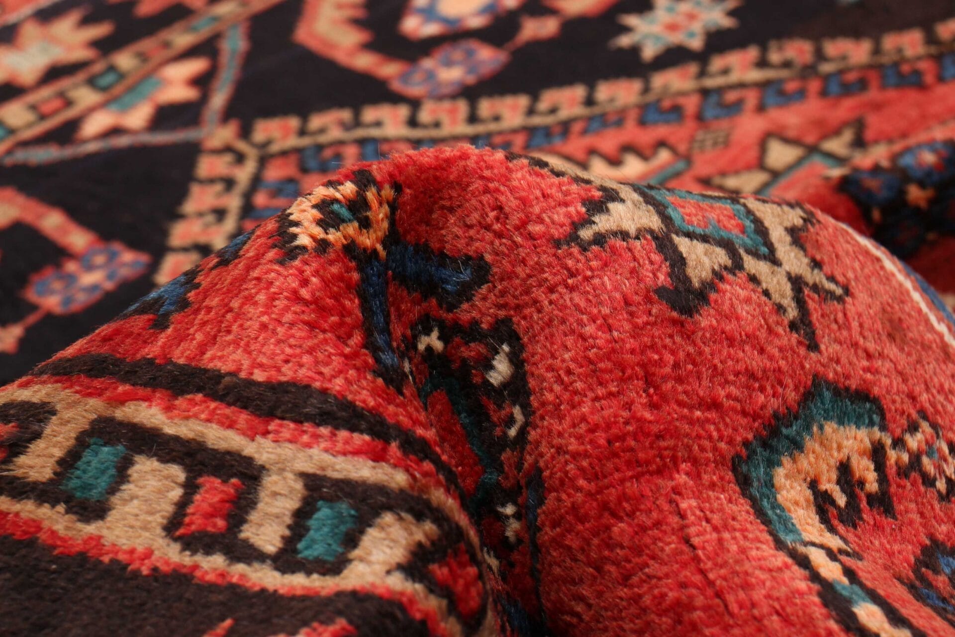 Een close-up van een vloerkleed in rood, blauw en zwart.