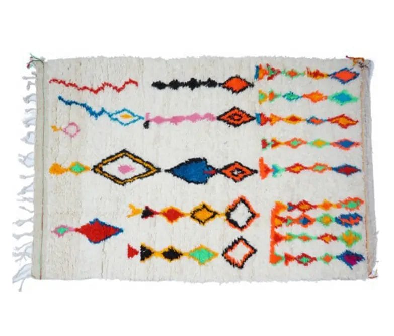 Handgemaakt Berber vloerkleed met een veelkleurig geometrisch patroon en franjes aan de linkerzijde, met diamant- en zigzagontwerpen op een witte achtergrond.