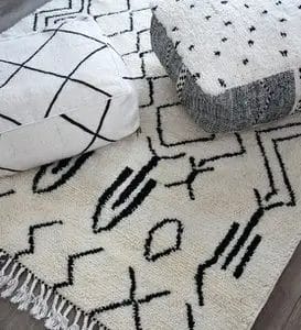 Wit tapijt met geometrisch patroon en twee vierkante kussens met zwart-witte dessins.
