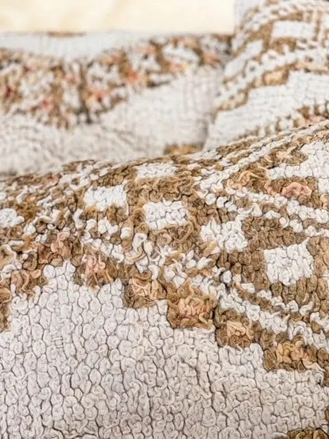 Close-up van een gestructureerde stof met een gedetailleerd beige en bruin patroon.