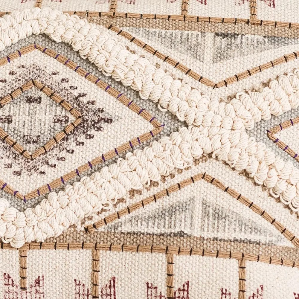 Close-up van een textielpatroon met geometrische vormen en ingewikkelde stiksels in beige-, grijs- en bruintinten.